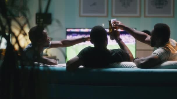 Amigos negros bebiendo cerveza durante el partido de fútbol - Metraje, vídeo