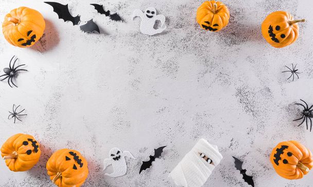 Halloween dekorace z dýně, papírových netopýrů a černého pavouka na kamenném pozadí. Flat lay, top view with copy space for text. - Fotografie, Obrázek