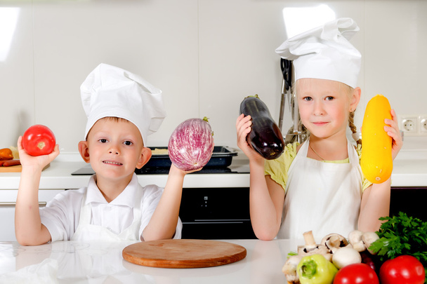 Kaksi hymyilevää lasta pitämässä tuoreita vihanneksia
 - Valokuva, kuva