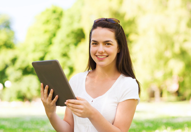 smiling young girl with tablet pc sitting on grass - Φωτογραφία, εικόνα