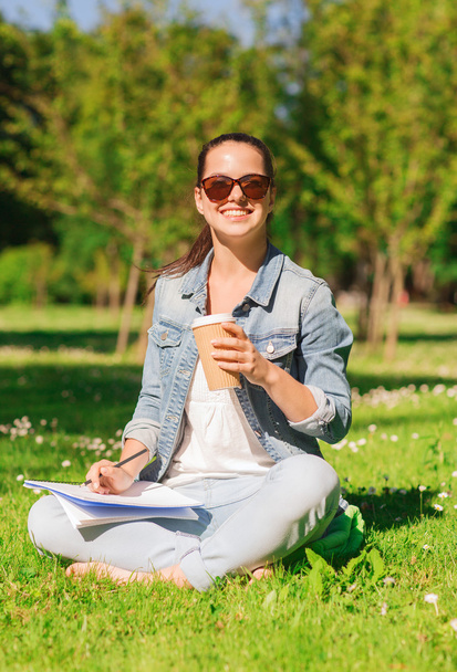 smiling young girl with notebook and coffee cup - Foto, imagen