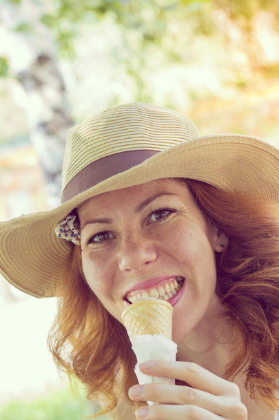 schönes lächelndes Mädchen mit Sommerhut, das Eistüte isst - Foto, Bild