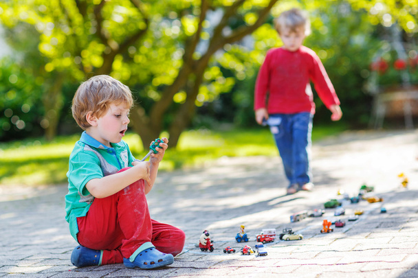 Duas crianças brincando com brinquedos de carro
 - Foto, Imagem