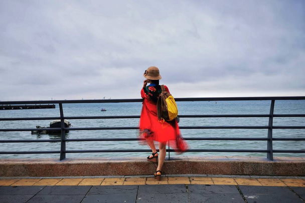 girl in a red jacket and sunglasses on the pier - Фото, изображение