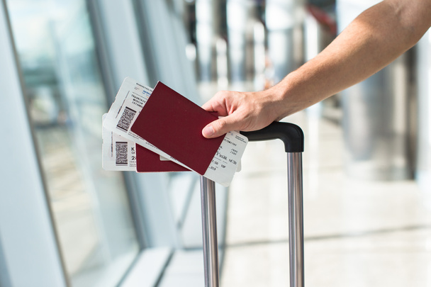 Gros plan des mains masculines titulaires d'un passeport et d'une carte d'embarquement à l'aéroport
 - Photo, image