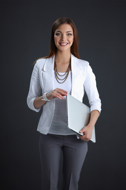 Young woman holding a laptop, isolated on grey background - Photo, image