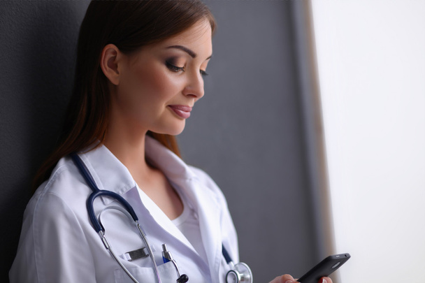 Young woman doctor sitting on the floor with your phone - Foto, Imagen