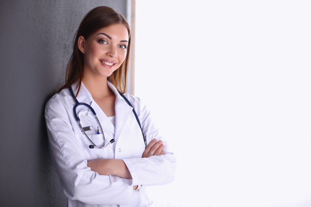 Doctor woman with stethoscope standing near grey wall - Fotó, kép