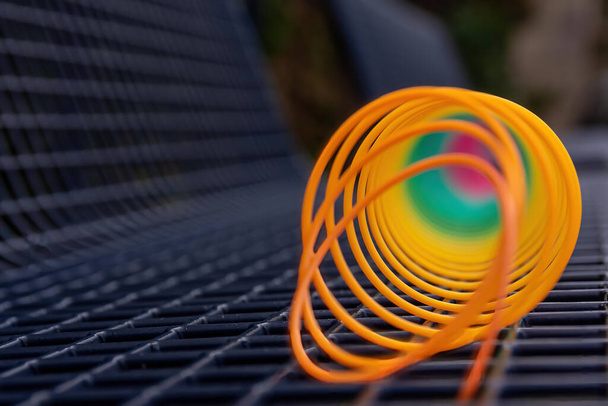 A selective focus shot of a spring toy on a lattice bench. - Foto, afbeelding