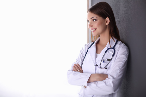 Doctor woman with stethoscope standing near grey wall - Foto, imagen