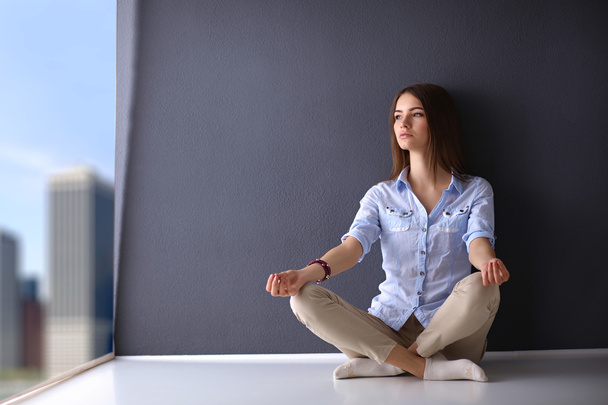 Young woman sitting on the floor  near wall ,doing yoga - Foto, Imagem