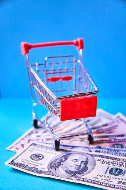concept - there is Shopping Cart Trolley on different dollar banknotes against the blue background - 写真・画像