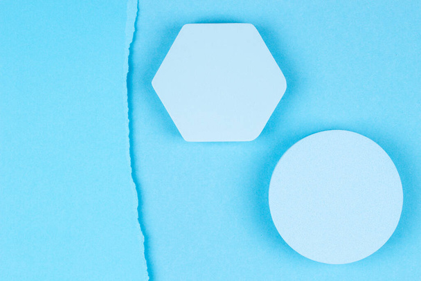 Fondo de color azul claro monocromo abstracto. Vista superior al podio geométrico de forma redonda y hexágono para la exhibición del producto, pieza de papel desgarrada sobre fondo de papel azul claro - Foto, imagen