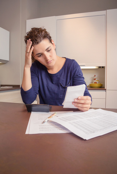 Безработная и разведенная женщина с долгами просматривает свои ежемесячные счета
 - Фото, изображение