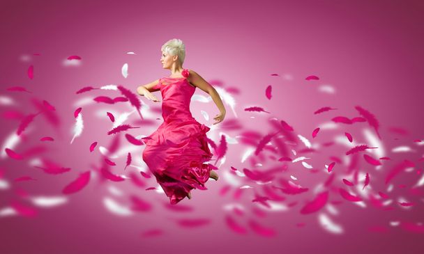 Woman in pink dress jumping - Foto, afbeelding