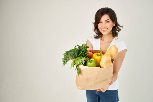 紙袋の食料品の野菜と陽気なブルネット - 写真・画像
