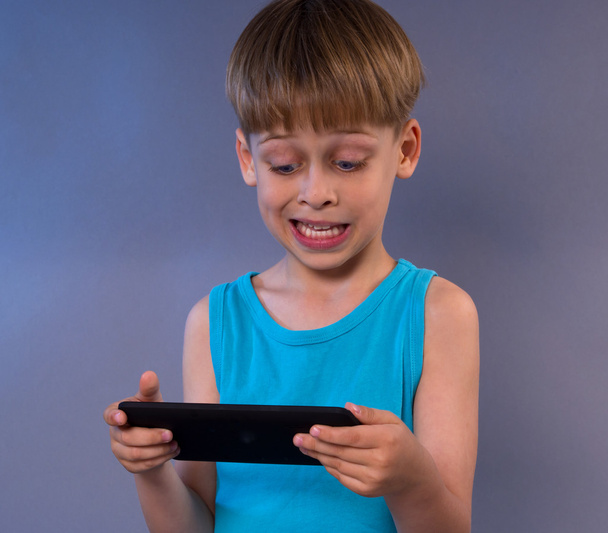 Мальчик играет в видеоигры на планшетном компьютере
 - Фото, изображение