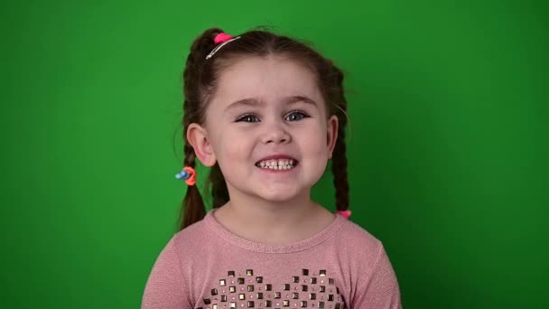 Klein en schattig meisje glimlachend, gelukkig en vrolijk baby, groene achtergrond. - Video