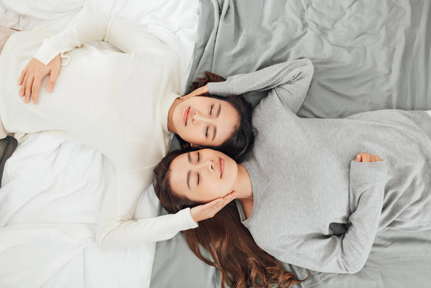 Overhead primer plano de joven pareja lesbiana acostada en la cama juntos. - Foto, Imagen