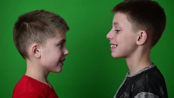 二人の男の子は歯垢を身に着けています,プロフィールの緑の背景のスタンドの子供たち. - 映像、動画