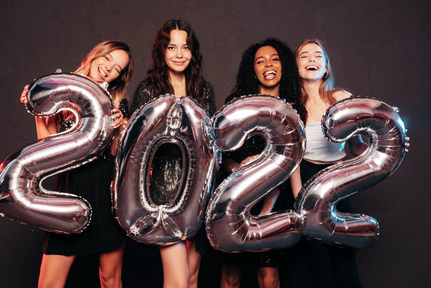 Beautiful Women Celebrating New Year.Happy Gorgeous Female In Stylish Sexy Party Dresses Holding Silver 2022 Balloons, Having Fun At New Year's Eve Party. Holiday Celebration.Charming Models  - Fotó, kép
