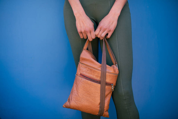 Καλλιεργημένη φωτογραφία γυναίκας που κρατάει δερμάτινη τσάντα - Φωτογραφία, εικόνα