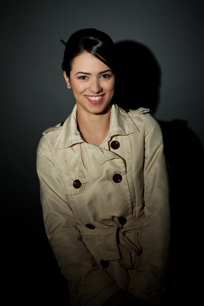 Nainen yllään trenssi takki ja hymyillen
 - Valokuva, kuva