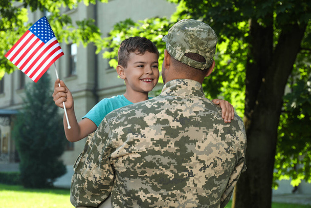 Soldier and his little son with American flag outdoors. Veterans Day in USA - Foto, imagen