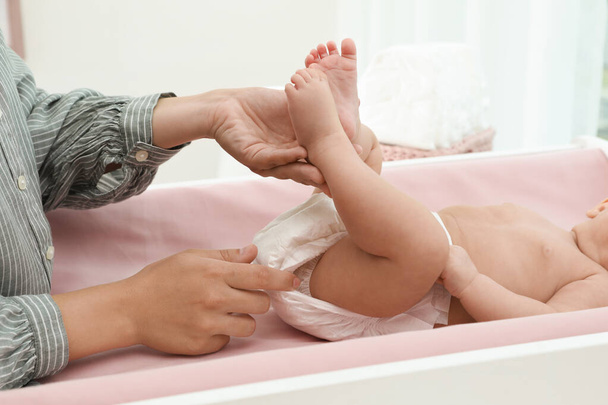 Mother changing her baby's diaper on table at home, closeup - Foto, afbeelding