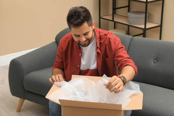 Man unpacking parcel at home. Online shopping - Foto, afbeelding