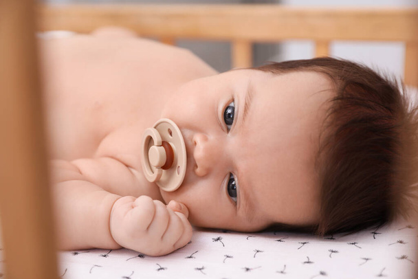 Cute little baby with pacifier lying in comfortable crib, closeup. Bedtime - Fotografie, Obrázek