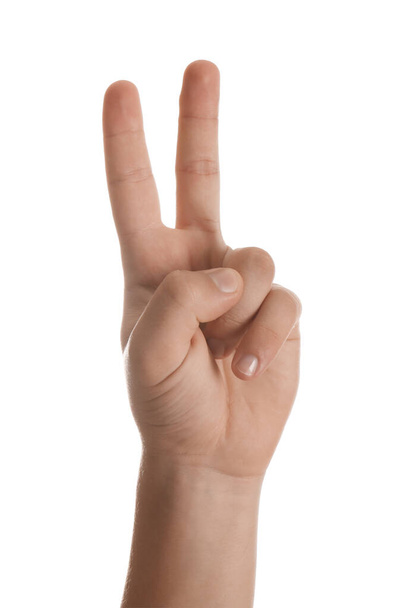 Teenage boy showing two fingers on white background, closeup - 写真・画像