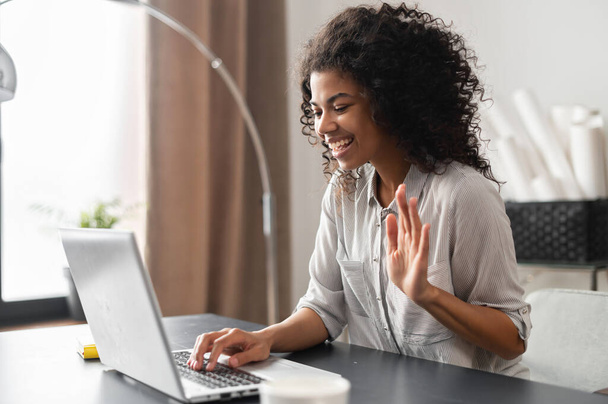 Biracial young woman with Afro hair using laptop indoor - Photo, image