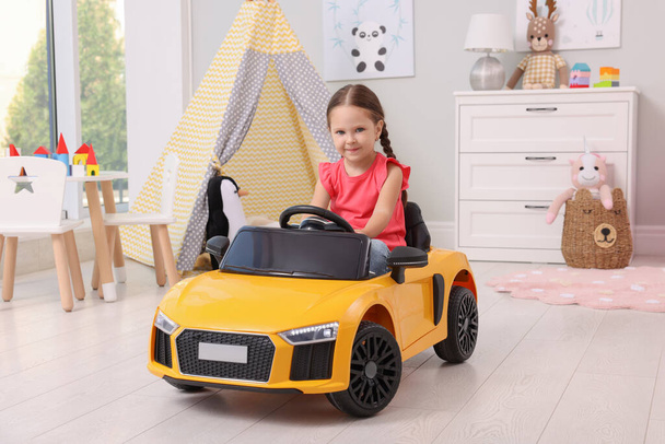 Adorable child driving toy car in room at home - Фото, изображение