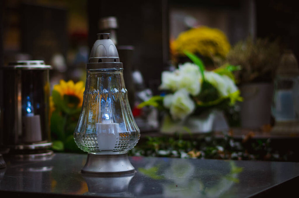 lucerny, svíčky a květiny během Dne Všech svatých na hrobě na hřbitově - Fotografie, Obrázek