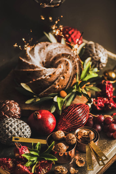 Christmas or Thanksgiving Day festive bundt cake with sparklers, nuts and baubles on kitchen counter. Winter holidays festive mood concept - Fotografie, Obrázek