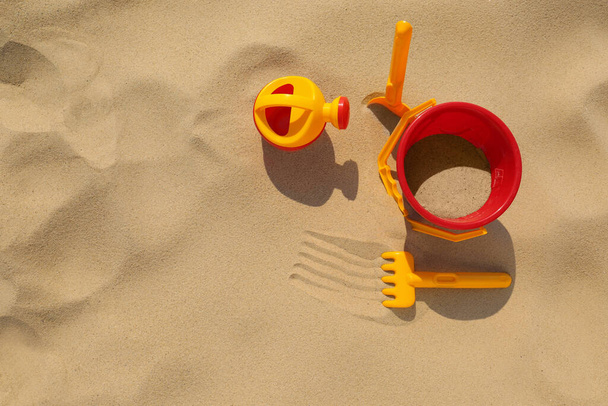 Set of plastic beach toys on sand, flat lay. Outdoor play - Foto, imagen