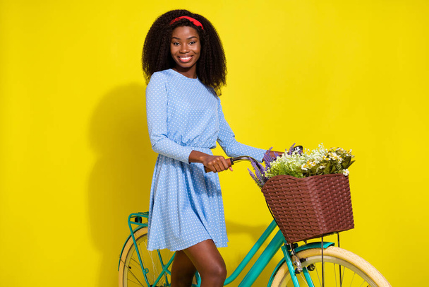 Photo portrait of girl in dress keeping retro bike with flower basket travelling in summer isolated bright yellow color background - Φωτογραφία, εικόνα