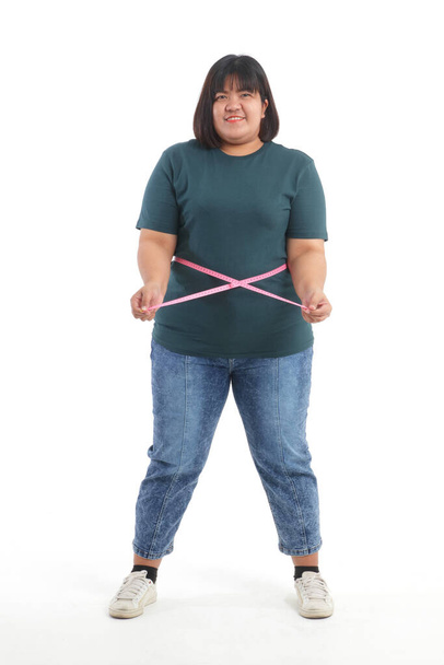 Obese vrouwen die proberen om gewicht te verliezen gebruik maken van een meetlint rond hun middel om hun maat te controleren. gewichtsverlies concept Om gezond te zijn. witte achtergrond - Foto, afbeelding