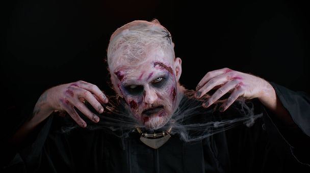 Hombre siniestro con horrible espeluznante maquillaje zombie muerto de Halloween disfrazado buscando ominoso en la cámara - Foto, imagen