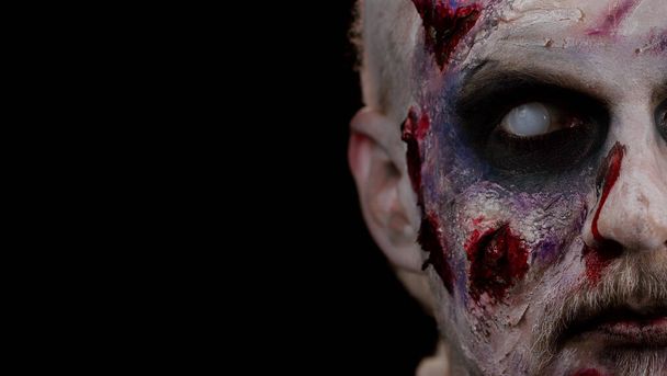 Close-up face of sinister man with horrible scary Halloween zombie makeup looking creepy at camera - Photo, Image