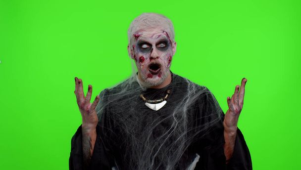 Gruseliger Mann Halloween-Zombie hebt überrascht die Hände und wirkt schockiert über plötzlichen Sieg, Chroma-Schlüssel - Foto, Bild