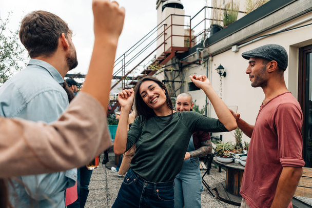 Leute haben Spaß bei Party auf der Terrasse - Studentin tanzt fröhlich unter Freunden auf dem Dach - Foto, Bild