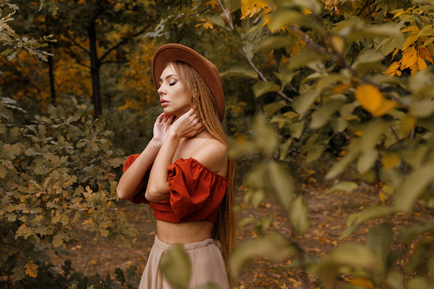 Μια νεαρή γυναίκα με φθινοπωρινό μακιγιάζ σε καφέ καπέλο στο δάσος του φθινοπώρου. κοντινό πλάνο - Φωτογραφία, εικόνα