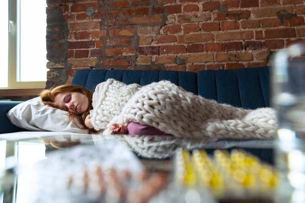Portrait recadré d'une jeune fille malade dormant sur un canapé. Auto-isolement et traitement à domicile - Photo, image