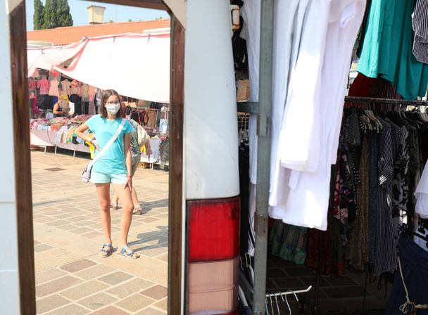 joven que se refleja en el espejo del puesto en el mercado al aire libre - Foto, imagen