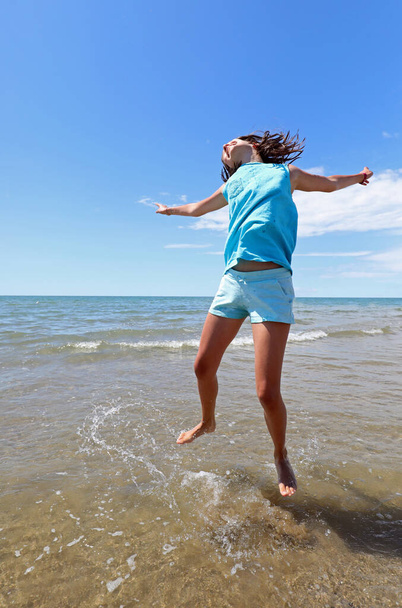 young cheerful girl by the sea making a big leap for joy - Photo, Image