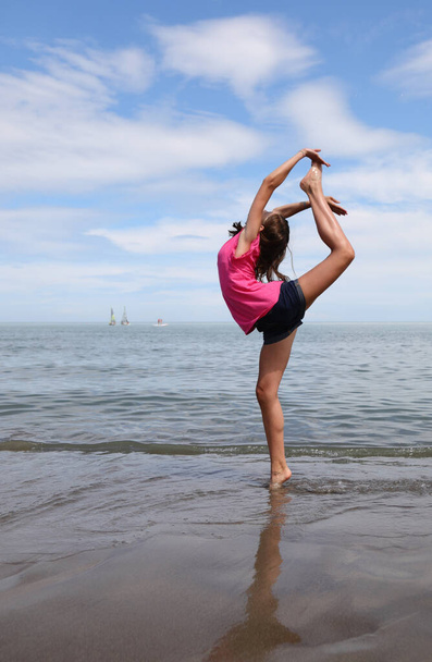 Genç beyaz kızlar yazın plajda ritmik jimnastik yapıyor. - Fotoğraf, Görsel