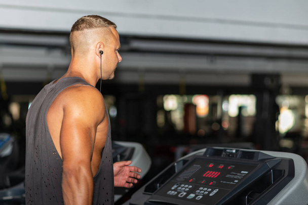 Young man in sportswear running on treadmill at gym.Handsome sport gym man running on the treadmill.Indoors shot.Man running in a gym on a treadmill.Healthy lifestyle concept.Copy space. - Photo, Image