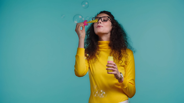 brunetka žena v brýlích foukání mýdlo bubliny izolované na modré - Fotografie, Obrázek